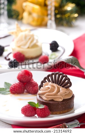 Chocolate cheesecake served with fresh raspberries, blackberries and mint. Delicious Vanilla Bean Cheesecake and Christmas ornament out of focus in background