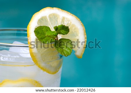 Closeup of glass of home made iced cold lemonade on hot summer on edge of swimming pool.