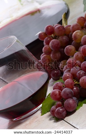 Glass of red wine, decanter and fresh cut red wine grape bunch.