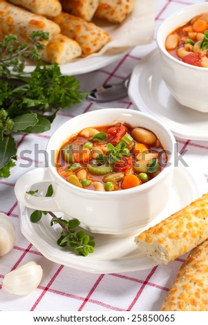 Two bowls of hot fresh Minestrone soup and cheese garlic bread sticks
