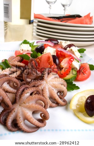Delicious cooked octopus in red wine dish and Greek salad