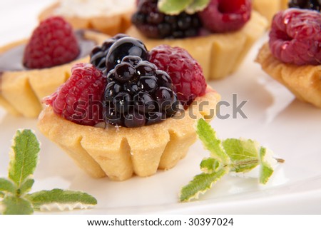 Full tray of delicious fresh berry cakes garnished with pineapple mint