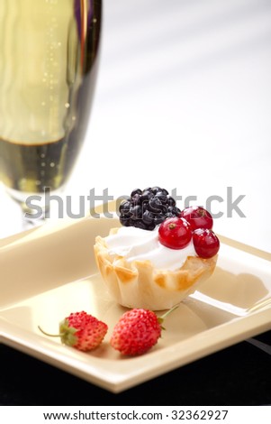 Closeup of delicious fresh berry cake and glass of champagne