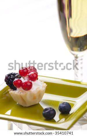 Closeup of delicious fresh berry cake and glass of champagne
