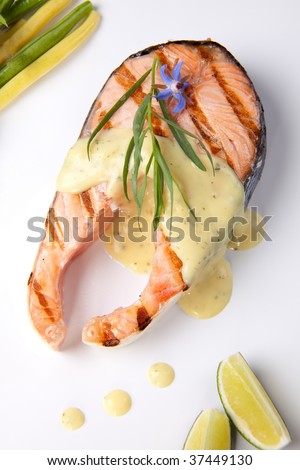 Closeup of delicious grilled salmon steak with tarragon sauce garnished with beans and cherry tomatoes.