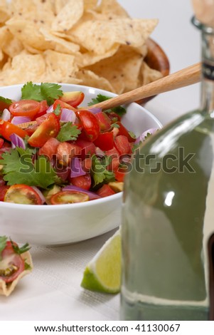 Bowl with fresh cherry tomatoes and avocado salsa. Corn chips and tequila.