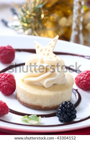 Delicious Vanilla Bean Cheesecake served with fresh blackberries and mint. Christmas ornament out of focus in background