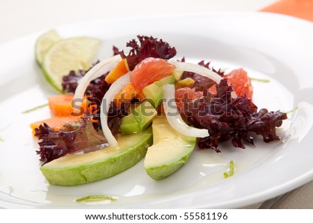 Closeup of papaya, avocado and grapefruit salad with sweet onion and lime wedges