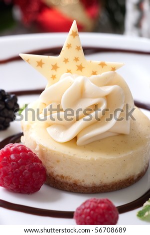 Delicious Vanilla Bean Cheesecake served with fresh blackberries and mint. Christmas ornament out of focus in background