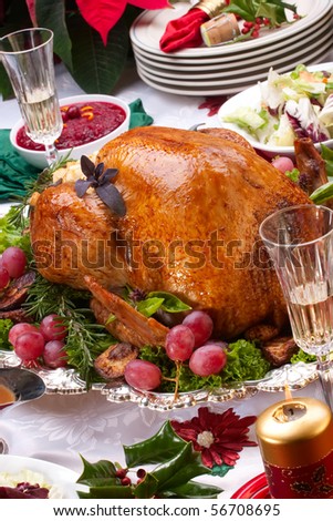 Garnished roasted turkey on Christmas decorated table with candles and flutes of champagne