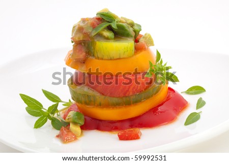Closeup of Heirloom Tomato Salad with basil avocado salsa over white.