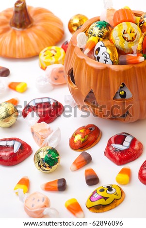 Scatter Halloween candies and orange pumpkin filled by them