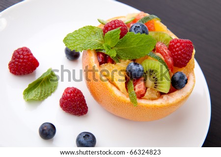 Serving of fresh fruit citrus berry salad in grapefruit peel. Kiwi, grapefruit, orange and pomegranate seeds.