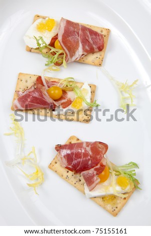 Crackers with goat cheese, apricot spread, and yellow pear tomatoes wrapped to prosciutto