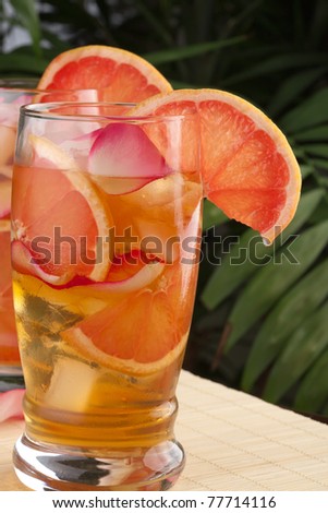 Closeup of glass of grapefruit and rose iced tea on a table in a restaurant on a tropical beach.