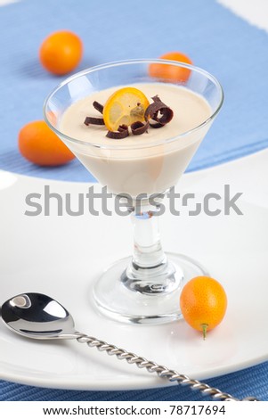 Closeup of Italian Panna Cotta Dessert in martini glass garnished with fresh citrus and chocolate swirls.