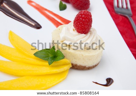 Delicious Vanilla Raspberry Cheesecake served with fresh mango and mint.