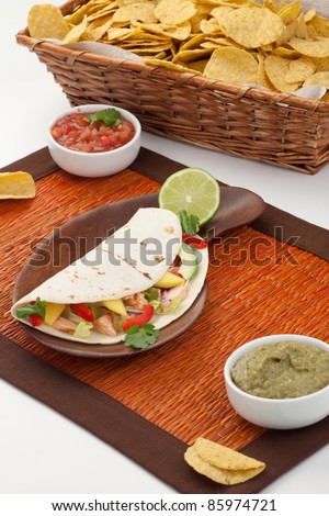 Closeup of grilled salmon fish tacos served with guacamole, fresh tomatoes salsa, and tortilla chips.