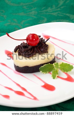 Closeup of delicious Chocolate Vanilla Cheesecake garnished with maraschino cherries and mint.