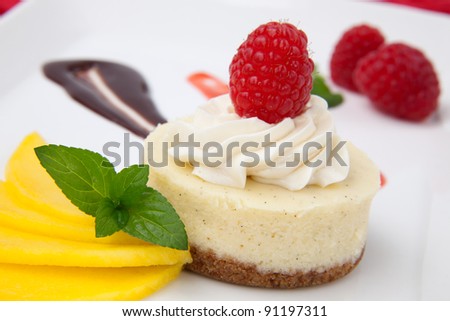 Delicious Vanilla Raspberry Cheesecake served with fresh mango and mint.