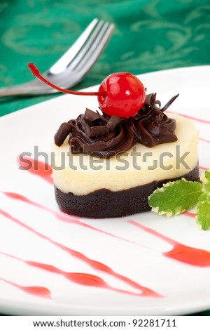 Closeup of delicious Chocolate Vanilla Cheesecake garnished with maraschino cherries and mint.