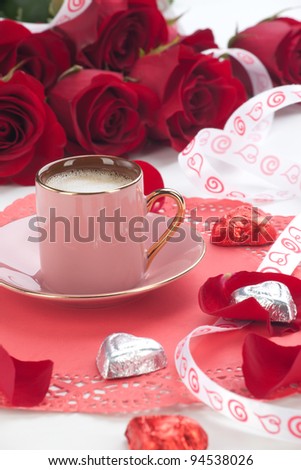 Closeup of cup of fresh coffee with red roses on Valentines day.