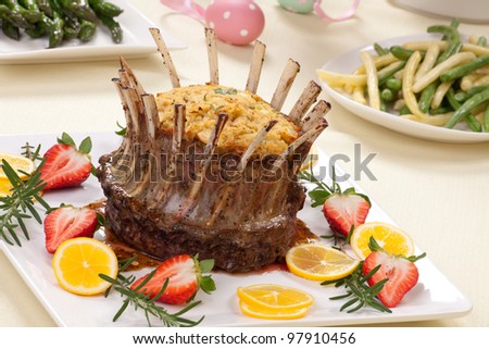 Crown roast of lamb with apple rosemary stuffing. Garnished with fresh strawberry, lemon, and rosemary twigs. Side dishes - asparagus, glazed carrots, and beans.