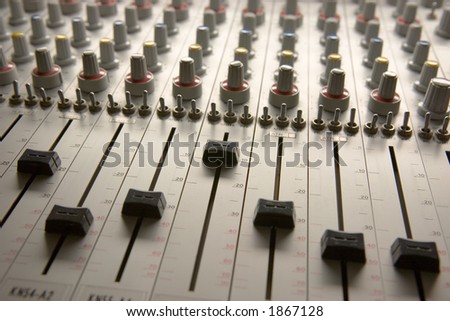 Professional audio mixing board with multiple channel faders and adjusting knobs