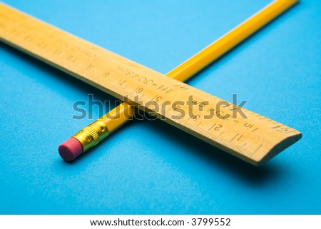 Wooden ruler and pencil crossed on blue background