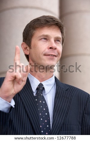 Man pointing up with index finger outside building