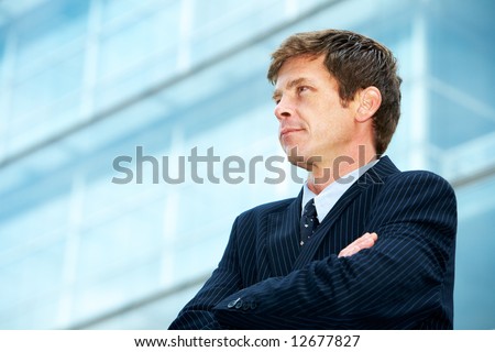 Man outside office building with arms crossed