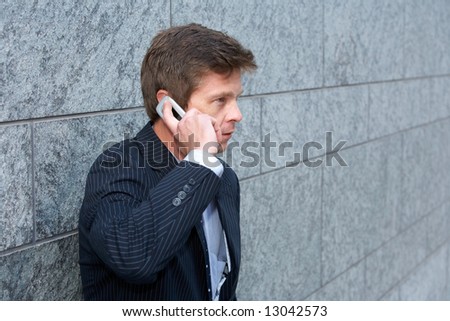 Man by building wall using cell phone