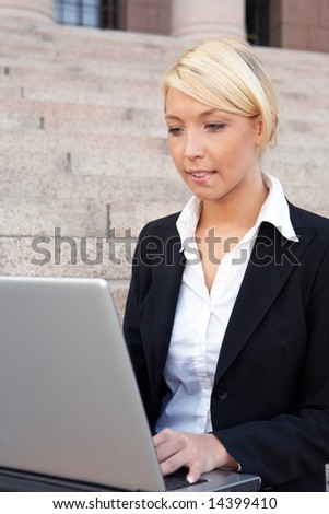 Businesswoman working with laptop computer outside building