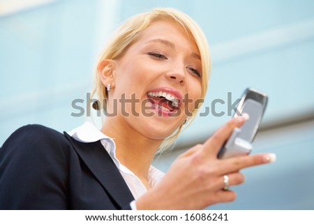 Young businesswoman looking at mobile phone outside office building
