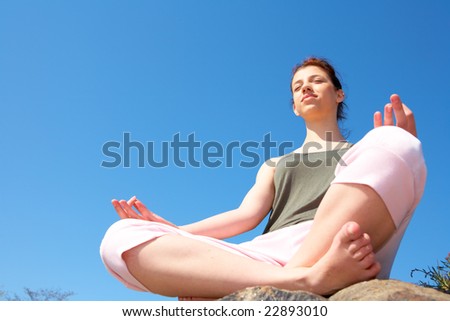 stock photo Teenage girl meditating bare feet on rock low angle