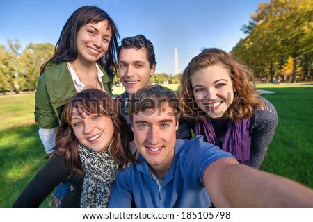 Group of early and middle 20s aged friends on a road trip to the nations capital takes a selfie (self portrait) with the Washington Monument in the background.