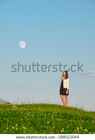 Young woman looking up at full moon.