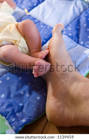 Father and newborn daughter compare feet