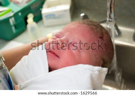 Newborn baby, just one hour old, getting first shampoo in hospital nursery.