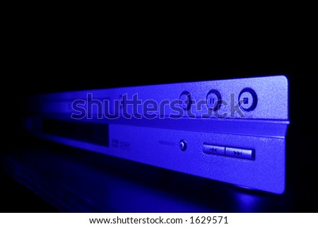 Modern DVD player lit by blue light and seen from an extreme angle.