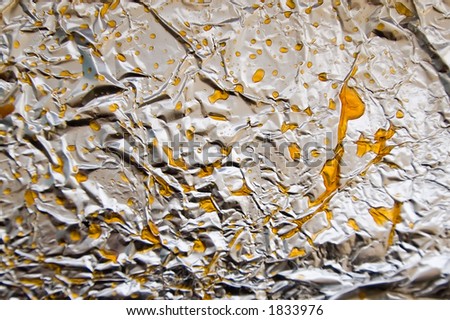 Abstract/Background actually made from greasy pizza left on tin foil. Focus is middle with some DOF blurring toward edges.