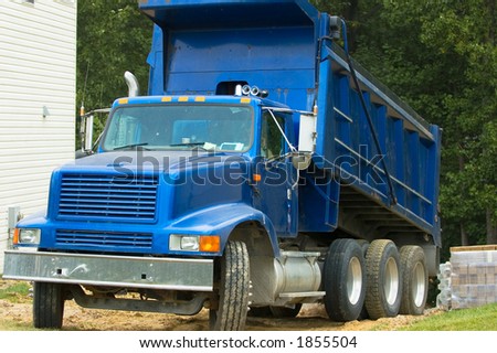Dump truck on a residential lot beginning to extend it\'s bed to dump it\'s payload.