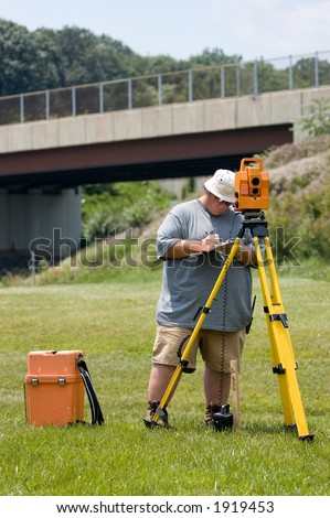 Land surveyor operating an electronic distance meter and recording measurements on a clipboard.