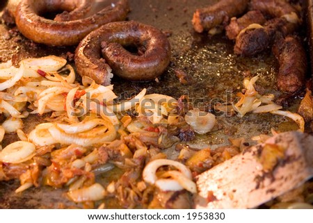 Tasty fair food! Italian Sausage and onions frying on an open grill.