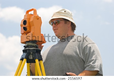 An instrument man, part of a two man land surveying crew, operates an electronic distance meter to make precise measurements on a construction site.