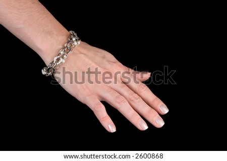 Hand with painted nails modeling a silver and pearl bracelet. Isolated on black background.