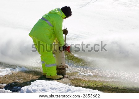 Worker in protective suit relieves intense pressure from a fire hydrant. Snow in the background gives good room for text.