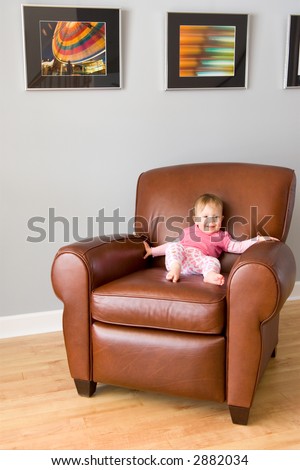 Baby girl as art enthusiast - sits on a leather recliner in an art gallery. Note: Author of this image is creator and copyright owner of photographs pictured, no trademark or IP issues.