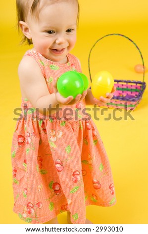 Cute baby girl in spring dress having fun playing with these new toys -- Colorful Plastic Easter Eggs! Moderately shallow DOF focus on babys's face and closest hand.