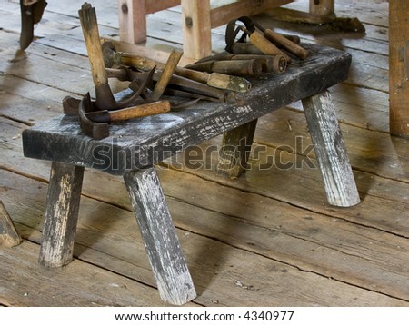 Antique wooden hand tools arrayed on an antique bench. Tools include hammers and axes used to build early America farms.